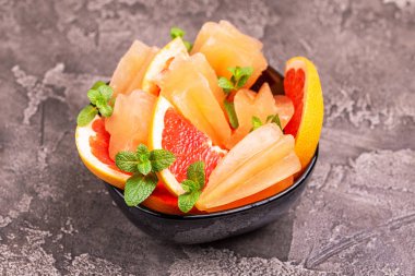 Ev yapımı greyfurt olgun greyfurt dilim ve karanlık beton zemin üzerine taze nane ile buzlu şeker. Sağlıklı tatlılar. Laktoz ücretsiz dondurma