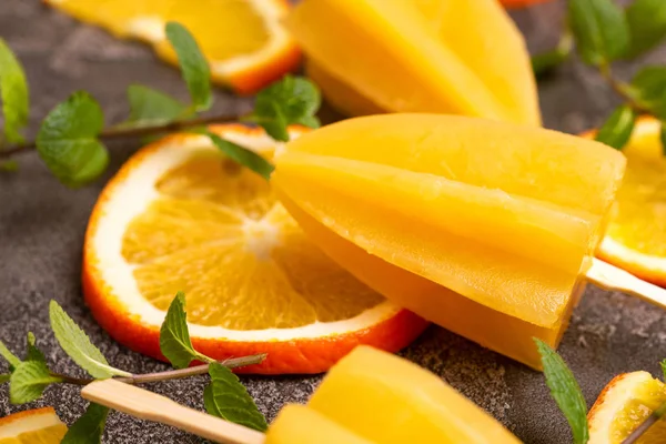 Gri beton zemin üzerine olgun turuncu ve taze nane ile ev yapımı turuncu buzlu şeker. Sağlıklı tatlılar. Laktoz ücretsiz dondurma.