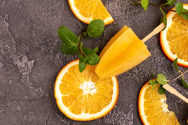 Gri beton zemin üzerine olgun turuncu ve taze nane ile ev yapımı turuncu buzlu şeker. Sağlıklı tatlılar. Laktoz ücretsiz dondurma.
