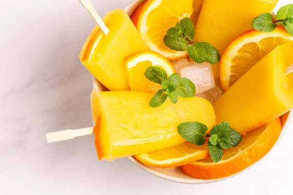 Işık mermer zemin üzerine olgun turuncu ve taze nane ile ev yapımı turuncu buzlu şeker. Sağlıklı tatlılar. Laktoz ücretsiz dondurma.