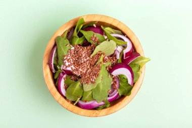 Açık yeşil arka planı üzerinde ahşap kase taze ıspanak, kırmızı soğan ve keten tohumu ile sağlıklı salata. Uzay kopyalayın. Üstten görünüm