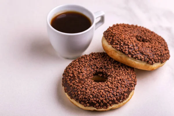 Bir kahve ışık mermer zemin üzerine serpin ve ile iki lezzetli çikolatalı çörek. Sağlıksız, ama lezzetli tatlılar. Uzay kopyalayın. Yatay görünüm