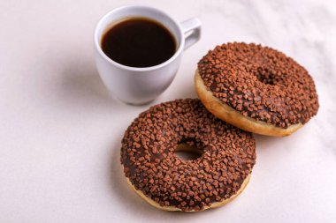 Bir kahve ışık mermer zemin üzerine serpin ve ile iki lezzetli çikolatalı çörek. Sağlıksız, ama lezzetli tatlılar. Uzay kopyalayın. Yatay görünüm