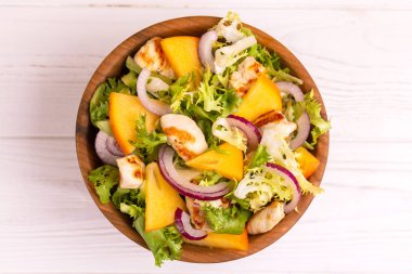 Frisee, Trabzon hurması, ızgara tavuk fileto ve susam ahşap kase lezzetli salata. Hafif ahşap arka plan. Uzay kopyalayın. Üstten görünüm