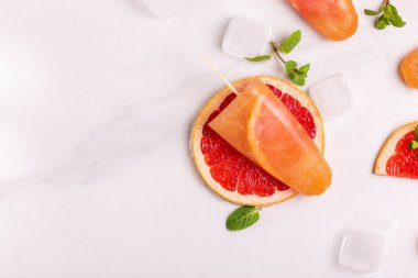 Ev yapımı greyfurt olgun greyfurt dilim ve ışık mermer zemin üzerine taze nane ile buzlu şeker. Sağlıklı tatlılar. Laktoz ücretsiz dondurma.