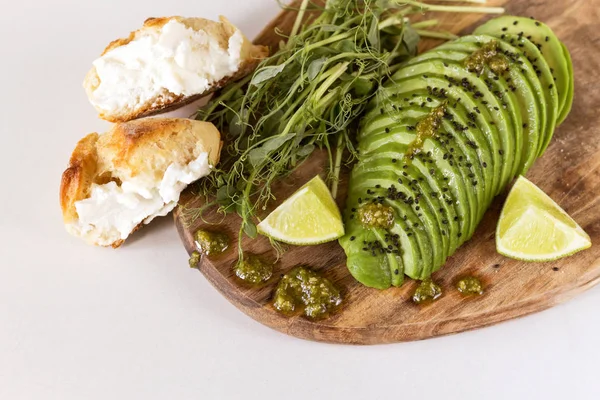 Ontbijt met avocado, broodje, erwten spruiten, limoen, pesto en koffie — Stockfoto