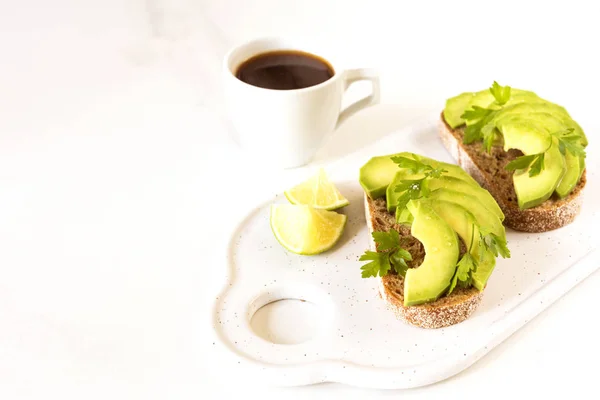 Gezonde ontbijttoast met avocado, limoen en koffie. — Stockfoto