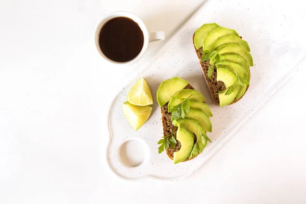 Torradas de pequeno-almoço saudáveis com abacate, lima e café . — Fotografia de Stock