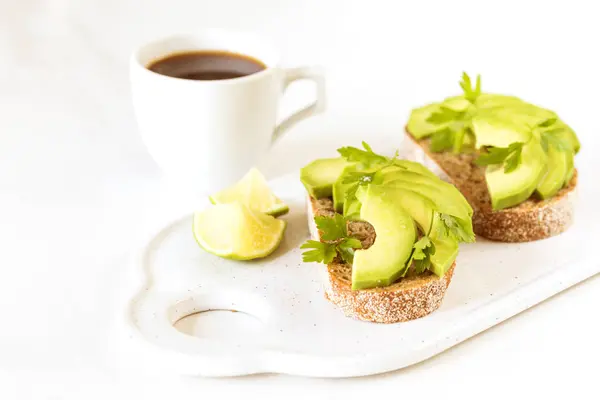 Gezonde ontbijttoast met avocado, limoen en koffie. — Stockfoto