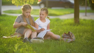 Bir kitap yaz bahçesinde çocuklar. Okul öncesi oyun arkadaşları ve öğrenme. Ödevlerini yapıyor kızlar.