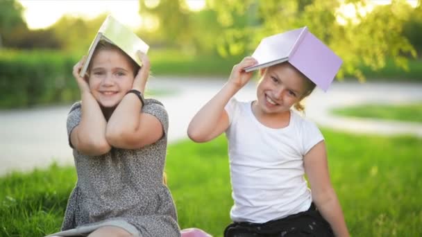 Deux filles drôles jouent avec des livres. Ils sourient et s'amusent beaucoup. Il fait beau. . — Video