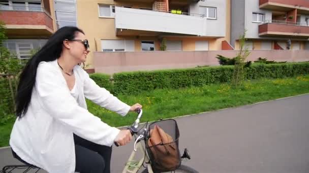 サングラスで自転車に乗って幸せな若い女性の肖像画。彼女の笑顔は美しい. — ストック動画