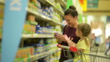 Tatlım Beyaz görünümü ile lolipop yemek ve süpermarket arabası içinde oturan kızdır. Anne arka plan bebek maması için kızını seçer.