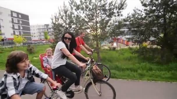 En familj tillbringar sommaren helgen tillsammans. De har mycket roligt för en tur på cyklar. — Stockvideo