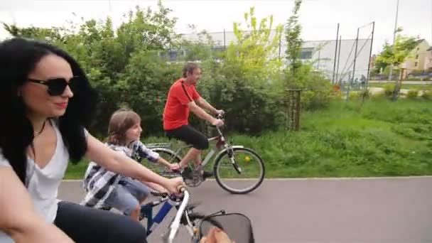 Una familia con apariencia caucásica obtiene el placer de dar un paseo en bicicleta. Tiempo de familia feliz . — Vídeos de Stock