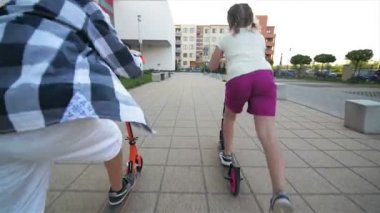 Çocuklar binmek Scooter için güneşli yaz gününde öğrenirler. Çocuklar açık havada scooter ile oynamak. Etkin boş ve çocuk için açık spor.