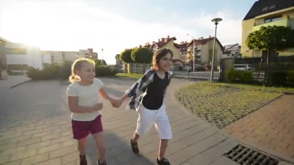 Menino e menina correm juntos segurando as mãos no asfalto. Eles têm um monte de diversão . — Vídeo de Stock