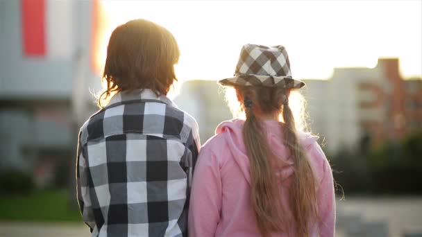 Två barn titta på varandra och skrattar. Flicka har en snygg hatt. — Stockvideo