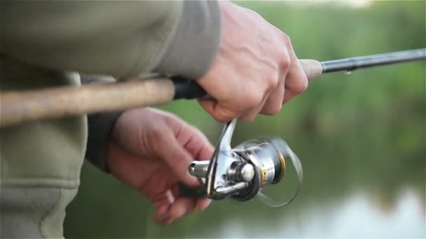 Fisher Man Mishing Over the Lake in primavera. Angler Holds canna da pesca. bobina è visto in un primo piano . — Video Stock