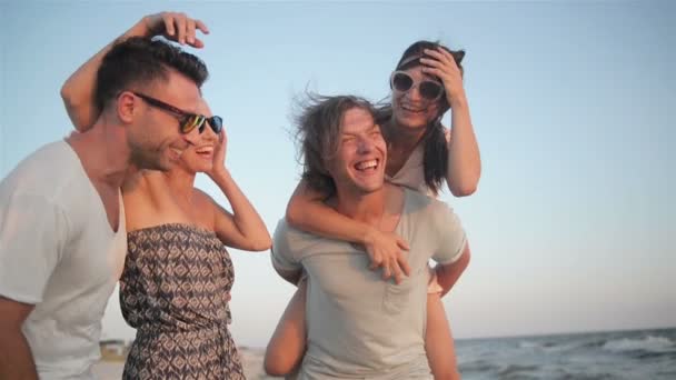 Retrato de un feliz grupo de jóvenes disfrutando de unas vacaciones en la playa. Cuatro amigos se ríen cerca del mar durante el verano . — Vídeos de Stock