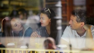 İçki ve kokteyller ile Cafe akşam yemeği masasında iyi vakit geçiriyor komik mutlu arkadaşlar portresi. Yakışıklı adam ve iki çekici kadınlar oturan büyük restoran penceresinde yakın:.