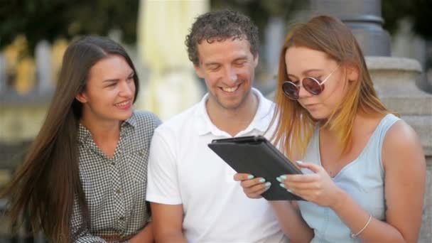 Closeup portret van drie studenten praten en studie samen buiten zitten op de Bank. Groep jongeren met notities, pennen en Tablet tijd buiten doorbrengen. — Stockvideo