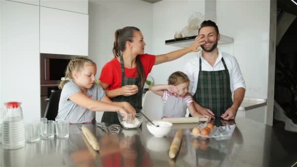 Семейная кухня вместе. У них много веселья, играя на кухне. Милые дочки со своими симпатичными родителями, играющими с мукой. Они улыбаются во время приготовления пищи . — стоковое видео