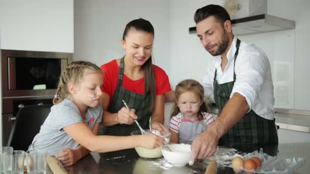 Birlikte yemek aile. Mutfak üzerinde oynarken eğlenceli bir sürü var. Un ile oynayan yakışıklı ebeveynleri ile şirin kız. Pişirme sırasında gülüyorsun. — Stok video