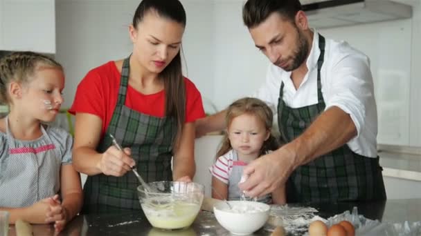 glückliche Familie Kochen zusammen. Kleine Töchter helfen ihren Eltern. Sie haben jede Menge Spaß.