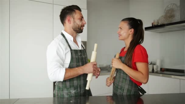 Portret van glimlachen paar In schorten verblijf in Lighty, moderne en ruime keuken. Ze hebben een heleboel plezier. — Stockvideo