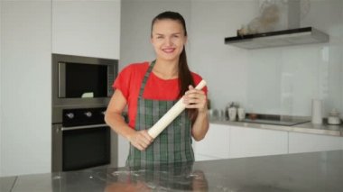 Çizgili önlük beyaz ev kadını gülümseyen genç. Mutfak arka plan üzerinde izole kırmızı T-Shirt. Güzel hizmetçi kadın portresi.