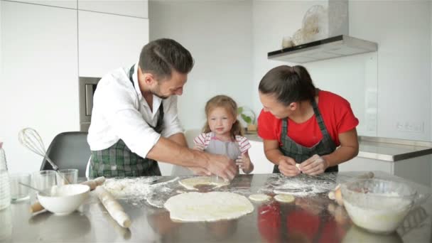 Nettes kleines Mädchen und ihre schönen Eltern kochen. Sie haben viel Spaß zusammen und lächeln in der heimischen Küche. hd, drei, glückliche Familie.