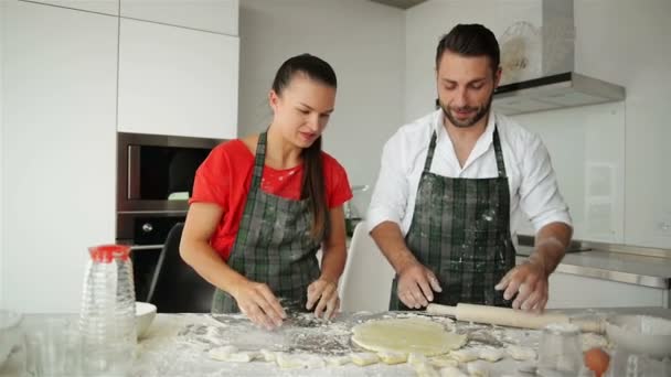 Engraçado casal amassar massa e se divertir com farinha na cozinha . — Vídeo de Stock