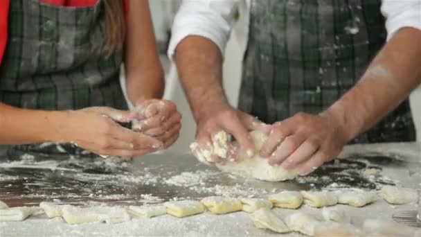 Pareja feliz cocinando juntos en la cocina. Se divierten mucho amasando masa y riéndose el uno al otro . — Vídeo de stock