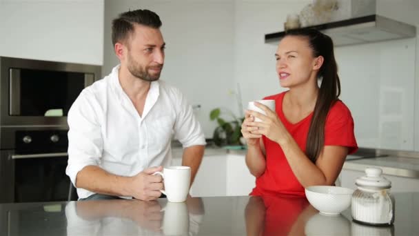 Mignon jeune couple buvant du café dans la cuisine. Ils ont une bonne humeur ce matin. . — Video