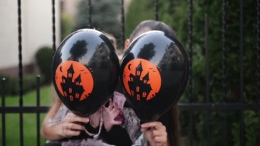 Sevimli kızıyla birlikte mutlu anne siyah balon tutuyor. Kızı olan Prenses Kostüm çünkü bugün Cadılar Bayramı. HD, eğlenceli, iyi Mood.