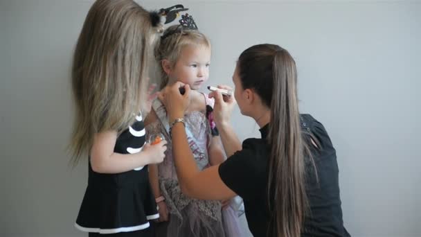 Mujer aplicando maquillaje de Halloween a la cara de sus hijas. Tienen un montón de diversión pasar tiempo juntos . — Vídeos de Stock