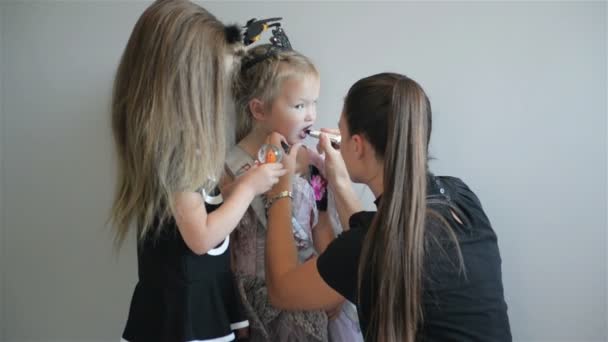 Женщина делает макияж на Хэллоуин перед лицом своих дочерей. У них много веселья, проводя время вместе. Хорошее настроение . — стоковое видео