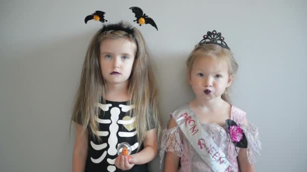 Duas irmãs engraçadas e fofas celebram o feriado. Crianças alegres em trajes de carnaval prontos para o Halloween . — Vídeo de Stock