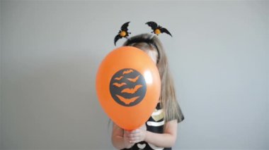 Gülümseyen kız mutlu portre içinde Halloween kılık giyinmiş hava balonları tutarak ve poz.