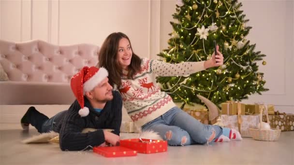 Счастливая молодая пара делает селфи в украшенной к Рождеству комнате. С Новым годом. Прекрасная семья . — стоковое видео