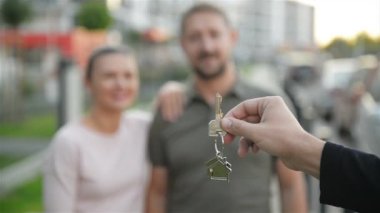 Bir el erkek emlakçı, yeni ev sahiplerine anahtarları verir. Mutlu çift.