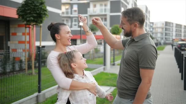大きな国の家の屋外の固定キーを立っている子供と幸せな家庭。高級不動産所有者カップルを笑顔し、子供通りに新しい家を購入した後。住宅ローンの貸付け金の概念. — ストック動画