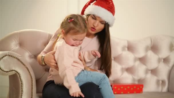 Küçük kız anne ellerinde ağlıyor. Genç Anne onun kızım sakinleştirmeye çalışır. Anneler günü, neşeli Noel, Yeni Yılınız kutlu olsun. — Stok video