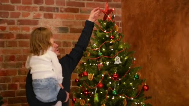 Giovane padre con carina figlia sulle sue mani stanno decorando l'albero di Natale. Felice anno nuovo. Festa dei Padri . — Video Stock