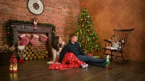 Family On Christmas Eve At Fireplace. Parents And Little Kid Opening Xmas Presents. Children With Gift Boxes. Living Room With Traditional Fire Place And Decorated Tree. Cozy Winter Evening At Home. — Stock Video
