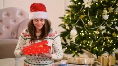Noel Baba şapkası kadınlarda portresi açılış hediyesi kutusudur. Noel ağacı üzerinde arka plan olduğunu. Mutlu yeni yıl kavramı.