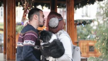 Mutlu çift açık havada eğleniyor. Noel zamanı ve mutlu yeni yıl kavramı. Aşık tatlı köpekleri tutuyorsun.
