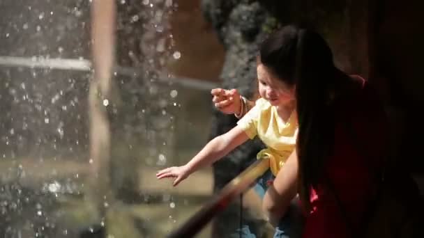 Mujer con su hija de pie cerca de la cascada. Están cansados pero felices de pasar tiempo juntos en la naturaleza . — Vídeos de Stock