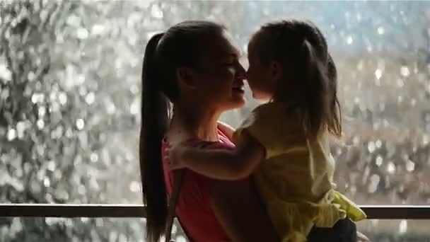 Mãe e filha felizes se divertindo no Dia das Mães. A cascata está no fundo. Mãe segurando seu filho. Close-up, Dia das Mães, Abraços . — Vídeo de Stock